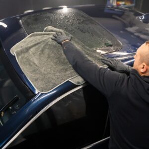 Car wash worker wipes the car after washing with microfiber towel. Professional car wash