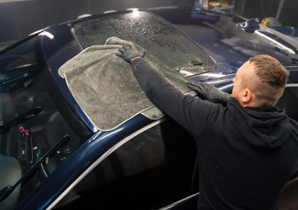 Car wash worker wipes the car after washing with microfiber towel. Professional car wash