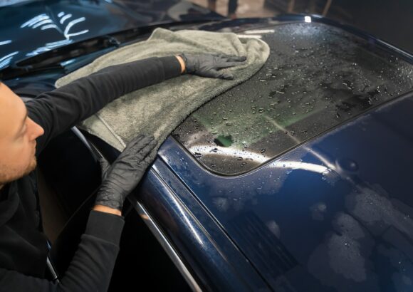 Car wash worker wipes the car after washing with microfiber towel. Professional car wash